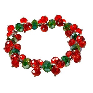 May include: A red and green beaded bracelet with a silver clasp. The beads are faceted and have a sparkly finish.