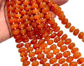 May include: A strand of orange carnelian beads with a pumpkin shape. The beads are smooth and polished, with a natural variation in color and pattern.
