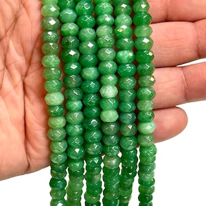 May include: Strands of faceted, round, green gemstone beads. The beads have a polished, glossy finish and are strung together. The beads are a vibrant shade of green, with variations in color. The beads are likely used for jewelry making.