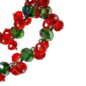 May include: A strand of red and green glass beads, strung together with silver metal connectors. The beads are arranged in a swirling pattern.
