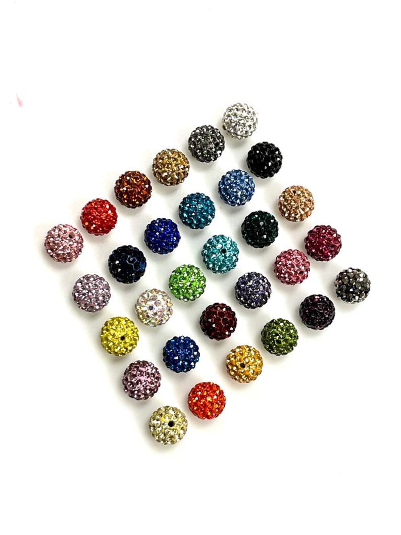 Peut inclure: Assortiment de 24 perles en strass color&eacute;es. Chaque perle mesure environ 2 cm de diam&egrave;tre et pr&eacute;sente une finition brillante et cristalline.