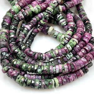 May include: A strand of green and pink gemstone beads. The beads are faceted and have a rough, natural look.