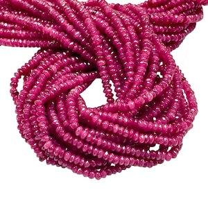 May include: A strand of pink ruby beads, faceted and round, with a smooth, polished finish. The beads are strung together to create a long necklace or bracelet.