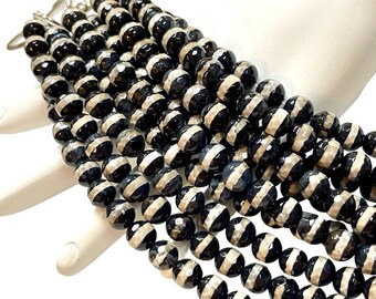 May include: Close-up of a multi-strand beaded necklace. The beads are black with a white stripe around the center. The necklace is made of round, faceted beads. The clasp is silver.
