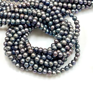 May include: Strands of dark gray freshwater pearls, with a subtle iridescent sheen. The pearls are round and uniform in size, creating a smooth, elegant texture. The beads are arranged in multiple strands, ideal for jewelry making.
