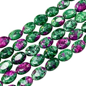 May include: Strands of oval-shaped beads. The beads are a mix of deep green and vibrant magenta colors. The beads have a polished, smooth surface and are strung together, creating a pattern of alternating colors. The background is plain white.