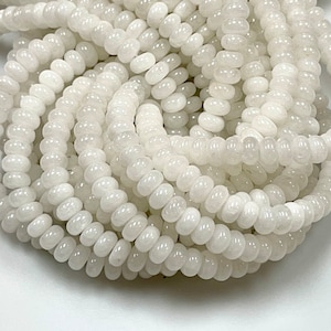 May include: Strands of white, disc-shaped beads. The beads are strung together, creating a textured, layered effect. The beads have a slightly glossy finish, reflecting light. Ideal for jewelry making.