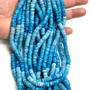 May include: A strand of light blue and dark blue gemstone beads. The beads are faceted and have a round shape. The beads are strung on a string and are ready to be used for jewelry making.