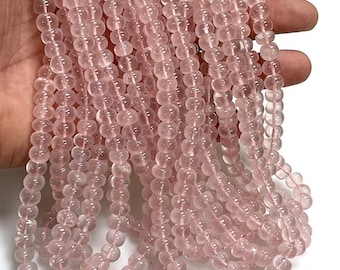 Può includere: Una collana di perle di quarzo rosa pallido. Le perle sono rotonde e lisce e sono infilate su un filo trasparente. Le perle hanno un diametro di circa 6 mm.
