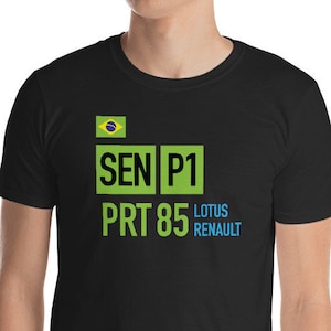 May include: Black t-shirt with a green and blue graphic design featuring the text "SEN P1 PRT 85 LOTUS RENAULT" and a small Brazilian flag.