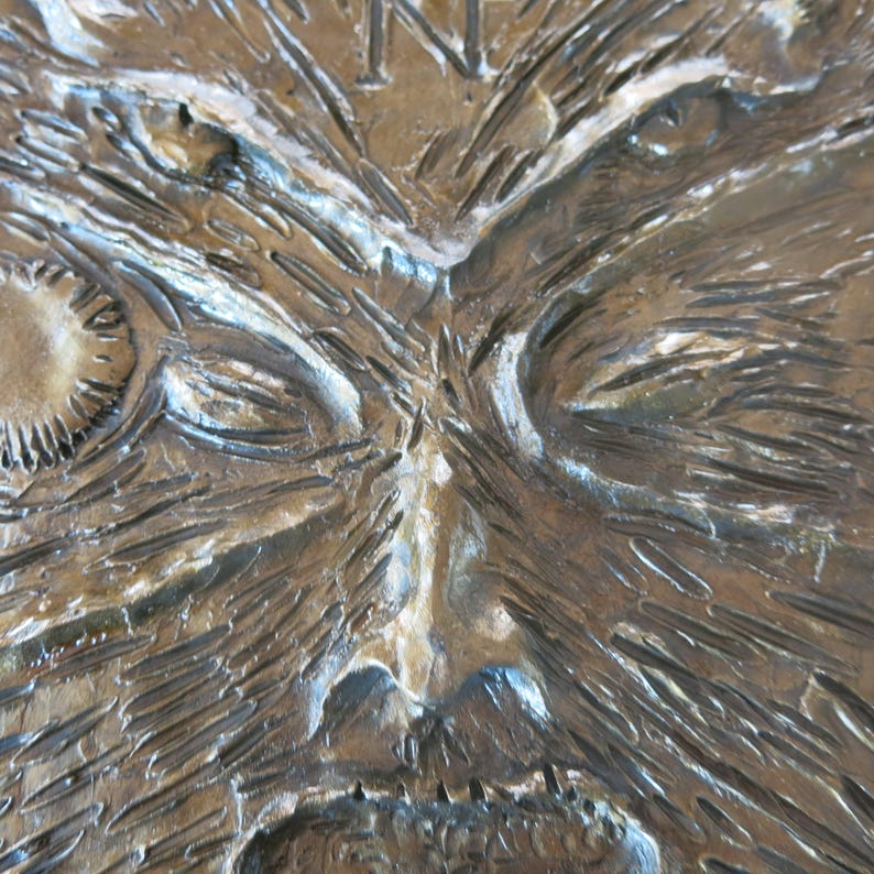 Puede incluir: Primer plano de una superficie de madera texturizada, marr&oacute;n, con una cara tallada. La cara tiene ojos hundidos, una nariz prominente y el ce&ntilde;o fruncido.