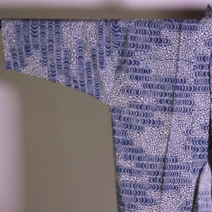 May include: A blue and white patterned kimono with a wave-like design. The kimono is open in the front and has long sleeves. The fabric has a dotted pattern in between the wave patterns.