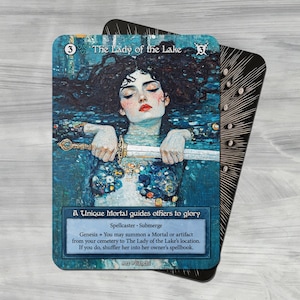 Può includere: Una carta da gioco fantasy che rappresenta una donna con lunghi capelli scuri, immersa nell'acqua, che tiene una spada. La carta è blu e bianca con il testo "The Lady of the Lake" e "A Unique Mortal guides others to glory".