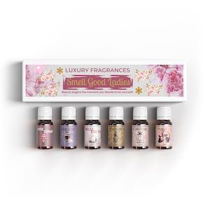 Peut inclure: Un ensemble de six petits flacons de parfum avec des bouchons blancs, disposés sous une boîte qui indique "Luxury Fragrances Smell Good Ladies". Chaque flacon a une étiquette unique avec des noms comme "Pink Sugar" et "Pussy".