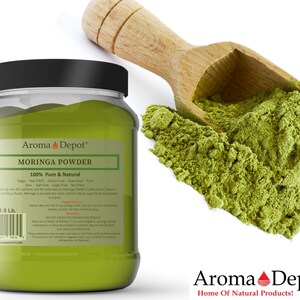 May include: A glass jar of green moringa powder with a 1.5 lb label. The jar is labeled "Aroma Depot" and "Moringa Powder 100% Pure & Natural". A wooden scoop with green moringa powder is in the background.