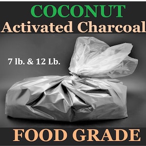 May include: A large, dark gray bag of coconut activated charcoal, tied at the top with a black twist tie. The bag is labeled with the text "COCONUT Activated Charcoal" and "FOOD GRADE". The bag is available in 7 lb. and 12 lb. sizes.