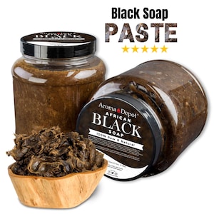 May include: Two glass jars of African Black Soap Paste, one open and one closed. The jars are labeled "Aroma Depot African Black Soap 100% Raw & Natural". The soap is a dark brown color and has a thick, creamy consistency. A small wooden bowl filled with the soap paste is in the foreground.