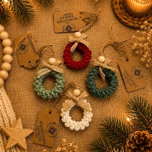 May include: Four small circular ornaments made of braided cord in red, sage green, dark green, and white. Each ornament features a natural wooden bead, a burlap ribbon bow, and a brown paper tag printed with The Wandering Thread logo.
