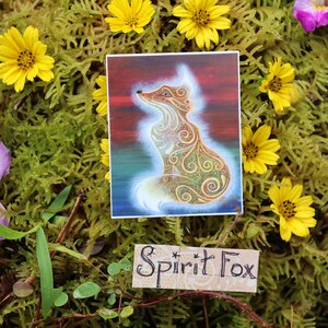 May include: A square sticker featuring a stylized fox with intricate patterns and a glowing outline, set against a colorful background. The sticker is surrounded by yellow flowers, green moss, and the text "Spirit Fox".
