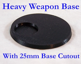 May include: A black, circular Heavy Weapon Base with a 25mm base cutout. The base is made of a solid material and has a textured surface. Text on the image reads "Heavy Weapon Base" and "With 25mm Base Cutout".