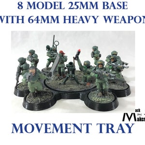May include: A black plastic movement tray for tabletop wargaming. The tray is designed to hold 8 miniature figures on 25mm bases, and includes a space for a 64mm heavy weapon. The tray features a green and brown textured surface, and the text "MOVEMENT TRAY" is printed on the bottom.