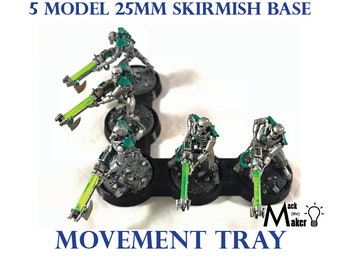 May include: Five silver and green miniature figures on a black movement tray with 25mm bases. The figures are holding weapons with glowing green tips. The tray has the text "Movement Tray" printed on it.