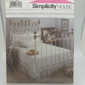 May include: Simplicity House sewing pattern for bedcovers, pillows, and shams. The package features a photograph of a white bed with a ruffled bed skirt and matching bedding. The pattern number is 8997, and it is one size.