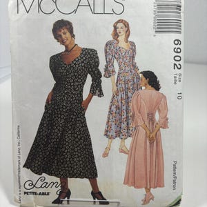May include: McCall's sewing pattern for a dress, size 10, with a floral print and puff sleeves. The pattern is called "Lanz Petite-Able" and has a model wearing a black and white floral dress, a pink dress, and a blue and white floral dress.