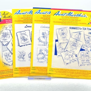 May include: Four Aunt Martha's hot iron transfer packets featuring blue line art designs for embroidery and fabric painting. The yellow paper envelopes display various illustrations including bunnies, colonial figures, and dogs with text labels.