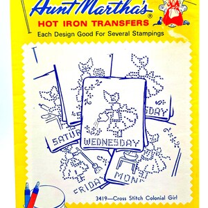 May include: A yellow Aunt Martha's hot iron transfers packet featuring blue line art designs of a girl performing daily chores. The text includes Aunt Martha's Hot Iron Transfers, 3419-Cross Stitch Colonial Girl, and days of the week labels.