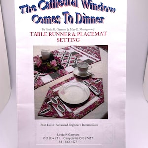 May include: A quilting pattern for a table runner and placemats featuring a cathedral window design. The pattern is titled "The Cathedral Window Comes To Dinner" and includes instructions for an advanced beginner or intermediate quilter. The pattern is by Linda K. Garmon and Mary E. Montgomery.