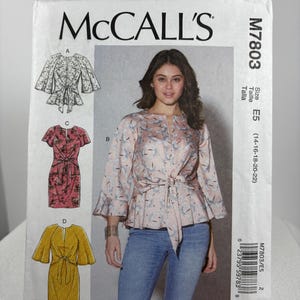 May include: A sewing pattern for a women's blouse with a tie at the waist. The pattern is for sizes 14-16-18-20-22. The pattern is from McCall's and the pattern number is M7803.