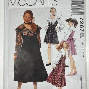 May include: A sewing pattern for a girls' dress with three different styles. The pattern is for sizes 10, 12, and 14. The pattern is from McCall's and the pattern number is 7267.