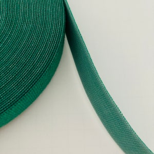 May include: A roll of green hook and loop tape, also known as Velcro, is displayed against a white background. The tape is a vibrant shade of green, with a textured surface. The roll is partially unraveled, showing the hook side of the tape.