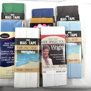 May include: A close-up of a variety of white bias tape packages. The packages are labeled with the brand name "Wrights" and the text "Wide Single Fold Bias Tape". The tape is 3 yards long and 22 mm wide. The packages are also labeled with the color "White 030".
