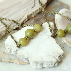 May include: A pair of long, dangling earrings with a bronze chain and three green jade beads.