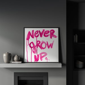 Puede incluir: Una impresi&oacute;n enmarcada con fondo blanco y letras de acuarela rosa que dicen "NEVER GROW UP."