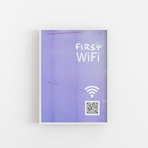 Könnte beinhalten: Ein weiß gerahmtes Schild mit einem violetten Hintergrund. Das Schild zeigt "FIRST WiFi" in weißer Schrift und hat ein WLAN-Symbol und einen QR-Code.