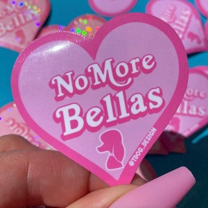 May include: Pink heart-shaped sticker with the text "No More Bellas" in white letters. The sticker has a glossy finish and a small pink poodle silhouette in the bottom right corner. The text "@TDOG_DESIGN" is in the bottom right corner.