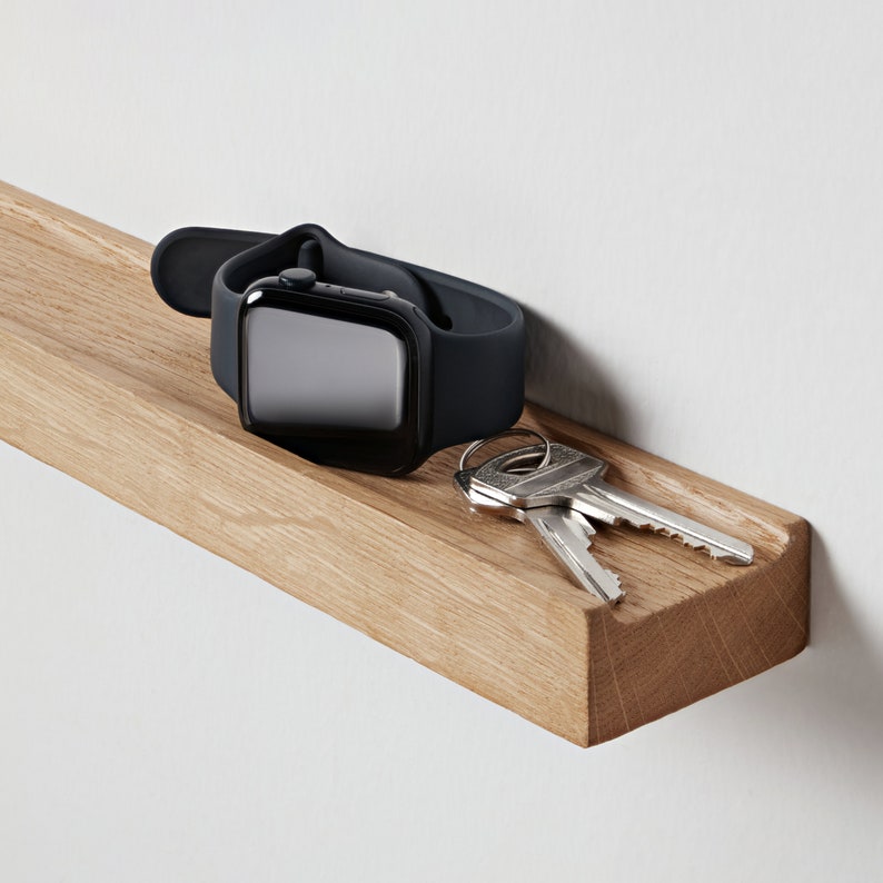 Puede incluir: Una estanter&iacute;a de madera con un reloj inteligente negro y dos llaves encima.