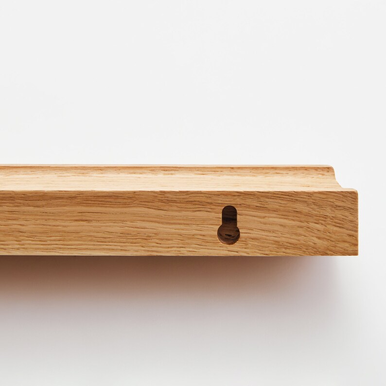 Puede incluir: Una estanter&iacute;a de madera marr&oacute;n claro con un borde redondeado y un solo agujero para colgar.