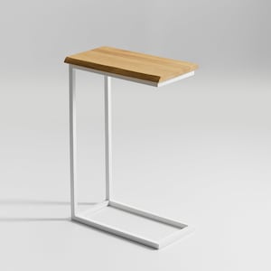 Könnte beinhalten: Weißer Metall-Beistelltisch mit einer natürlichen Holzplatte. Der Tisch hat ein schlichtes, modernes Design.