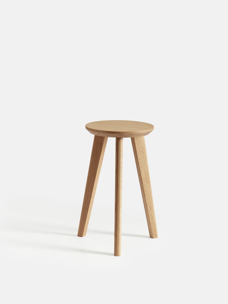 May include: A light brown wooden stool with a round seat and three legs.