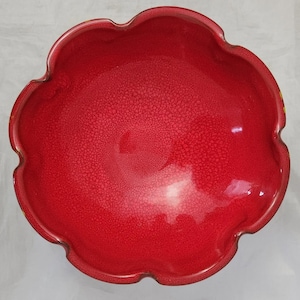May include: A vibrant red, scalloped-edge bowl with a textured surface. The bowl's interior and exterior are a deep, glossy red, creating a striking contrast. The unique shape and color make it a decorative piece.