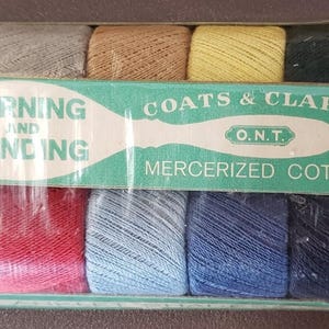 May include: A vintage package of Coats & Clark's O.N.T. mercerized cotton thread for darning and mending. The package contains ten spools of thread in various colors, including white, gray, tan, yellow, green, pink, red, blue, and navy. The package is marked "15¢".