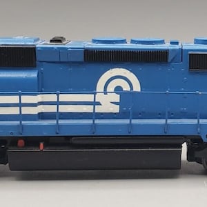 May include: A blue model diesel locomotive train engine featuring the white text CONRAIL and the number 6478 on the side. The train has black wheels, a white circular logo, and white horizontal stripes along the body with black vents.