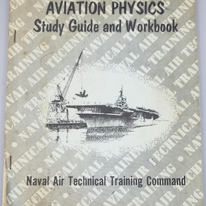 May include: A softcover book titled Aviation Physics Study Guide and Workbook by the Naval Air Technical Training Command. The cover features a black and white illustration of an aircraft carrier with a crane and a plane, set against a repeating background pattern of the text Naval Air Technical Training.
