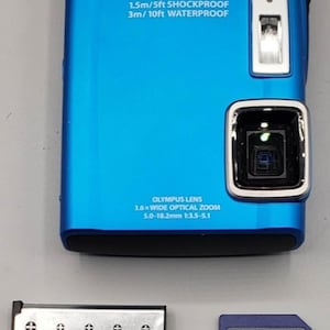 Puede incluir: Cámara digital Olympus Tough azul con lente de zoom óptico gran angular 3.6x, resistente a golpes de 1.5 m y resistente al agua a 3 m. Incluye batería y tarjeta Secure Digital de 2 GB.