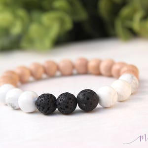 May include: A bracelet made with brown wood beads, white beads, and black lava rock beads.