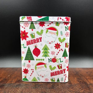 May include: Rectangular metal tin with a festive Christmas pattern. The design includes Santa Claus faces, Christmas trees, poinsettias, holly, and the words "MERRY" and "NOEL" in red and green on a white background.